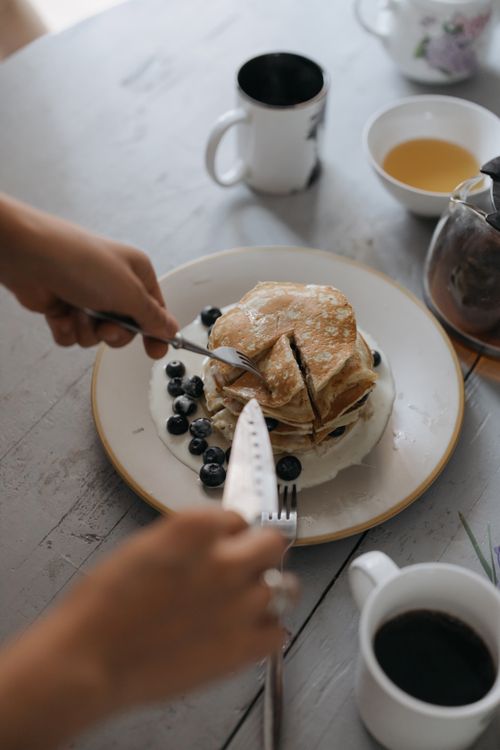 Free Fresh pancakes served with blueberries and coffee on a rustic table setting. Stock Photo