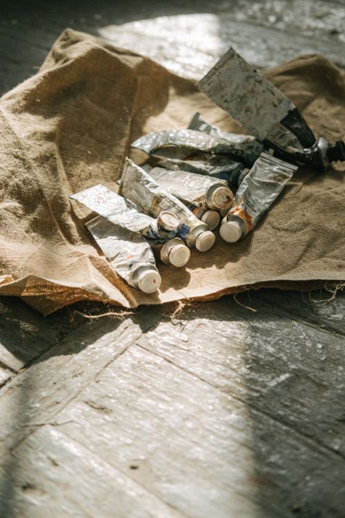 Free A collection of used paint tubes resting on rustic fabric, bathed in natural light. Stock Photo