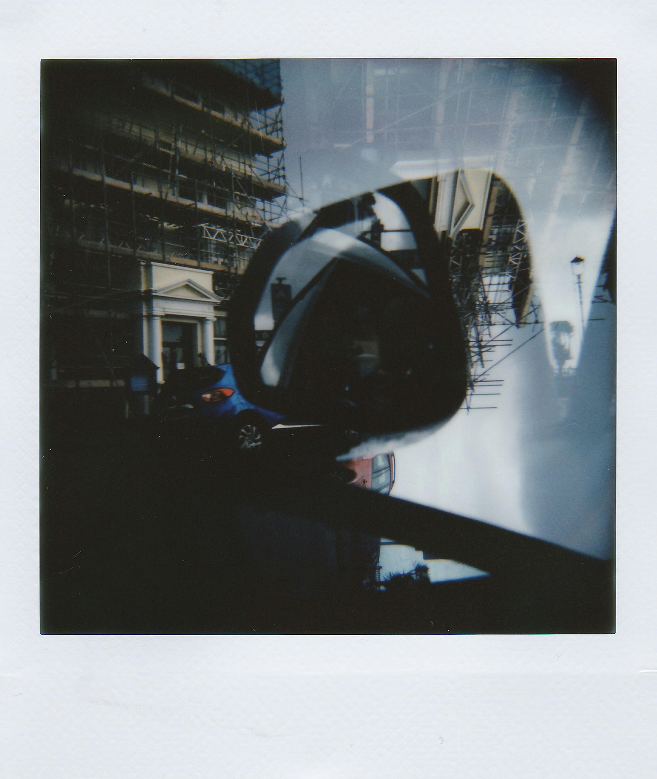Artistic double exposure photo of city street reflecting in a car's side mirror.