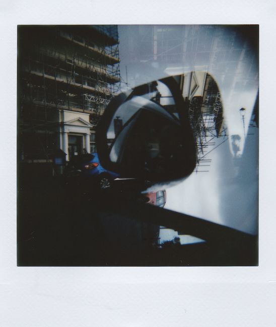 Artistic double exposure photo of city street reflecting in a car's side mirror.