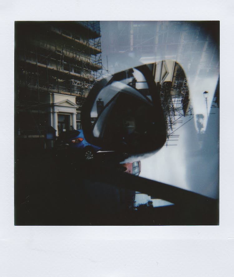 Polaroid Double Exposure Picture Of A Side Mirror In A Car And City Street 