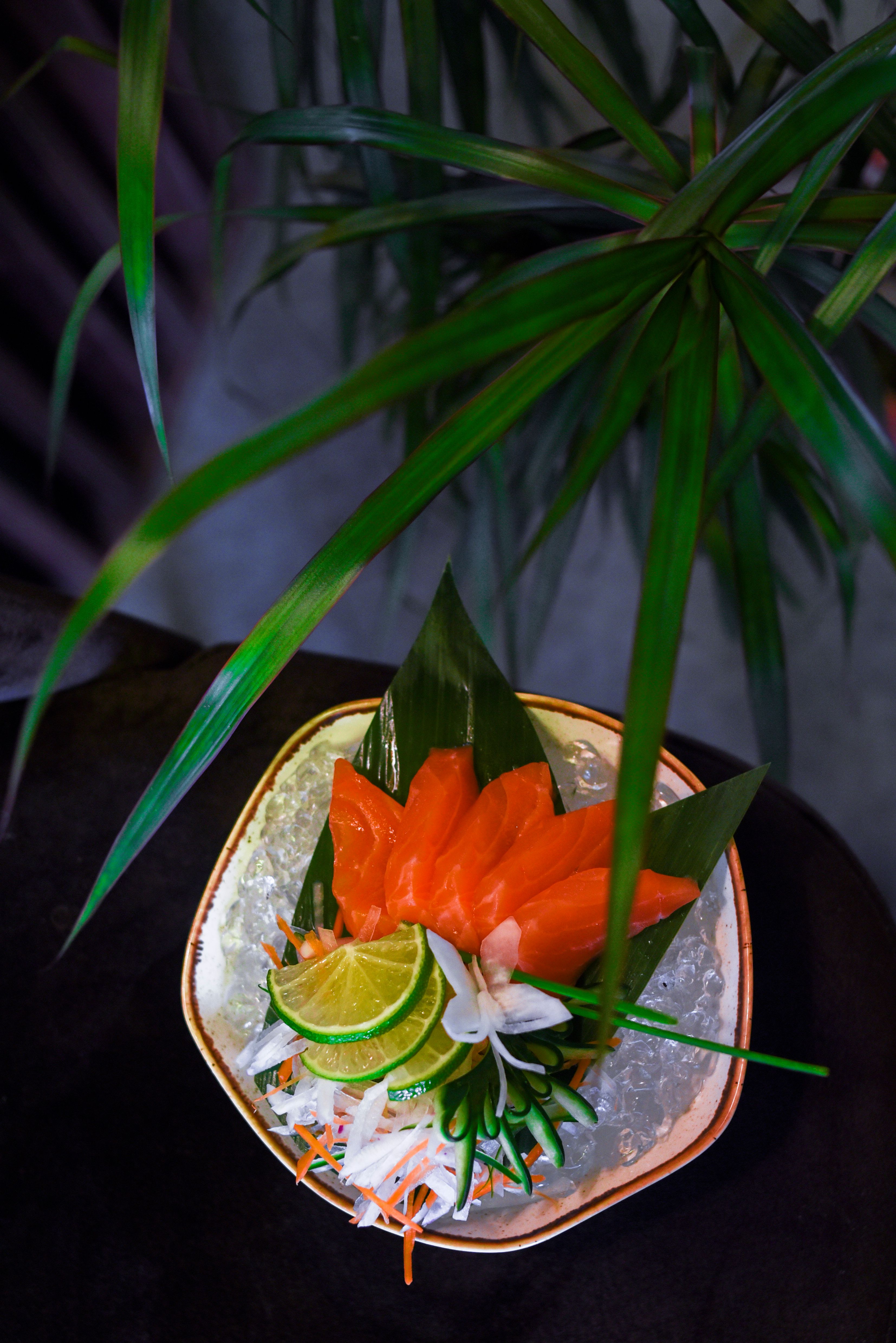 特写三文鱼生鱼片，优雅地配上酸橙片和绿叶，非常适合美食摄影