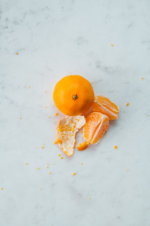 Free Top view of vibrant whole orange and slices of fruit by skin on table in bright room Stock Photo
