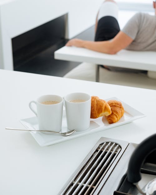 Croissants and cups of coffee on table in bright room