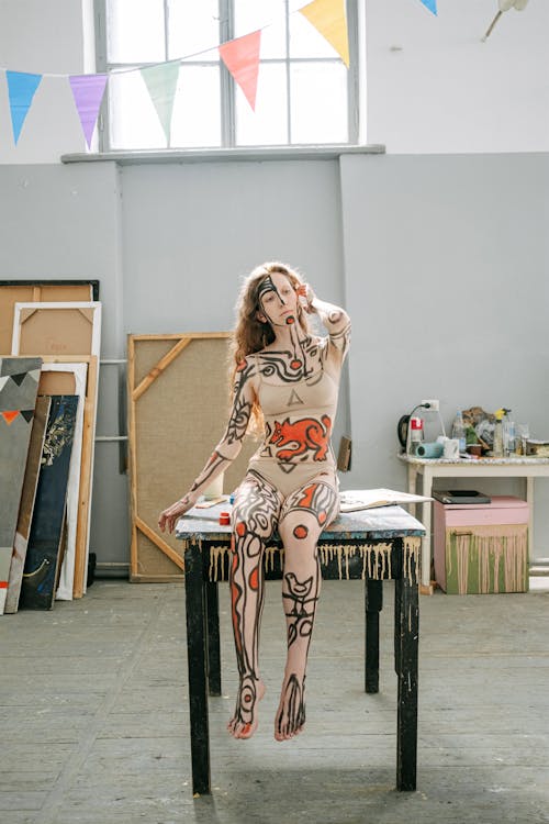 A Woman with Red and Black Body Paint Sitting on a Table