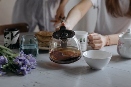 Free Person Holding Teapot while Breakfast at the Table Stock Photo