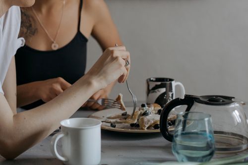 Free Two women savoring breakfast with pancakes and coffee, creating a cozy morning scene. Stock Photo