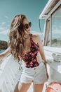 Stylish young lady standing near deckhouse of white yacht