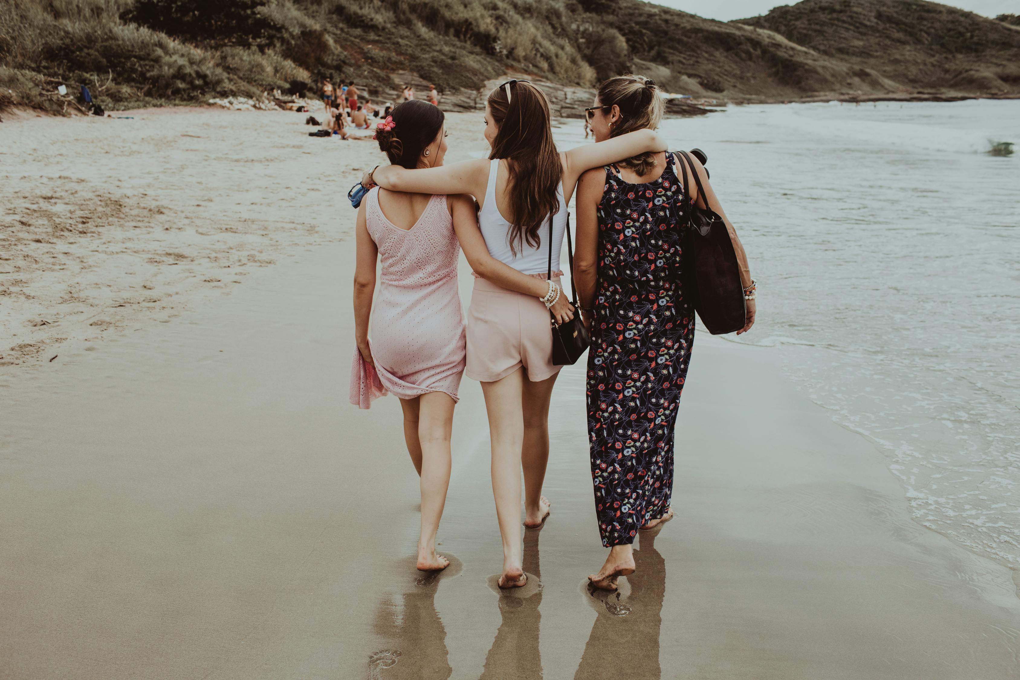Cheerful girlfriends walking together along sandy beach · Free Stock Photo