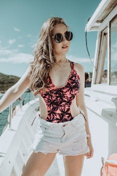 Stylish woman in sunglasses and swimsuit relaxing on a yacht, soaking up the sun.