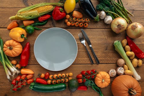 Plate and Fresh Vegetables on Wooden Table