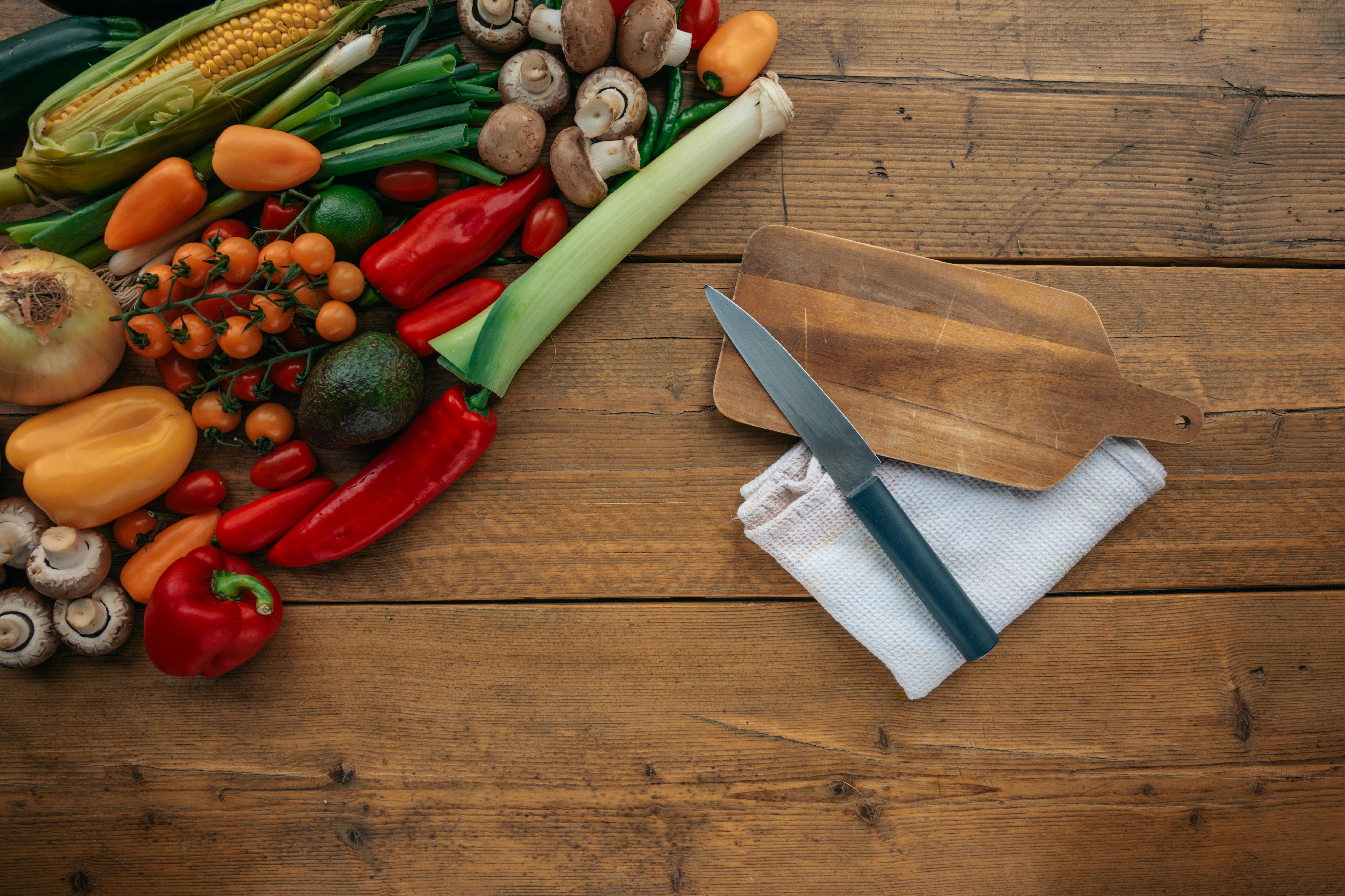 Fresh vegetables on woden cutting board with knife