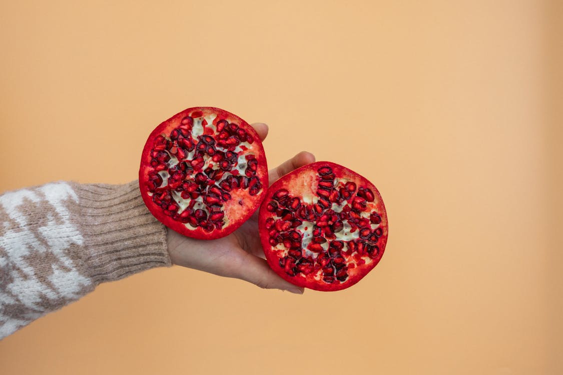 Free A Person Holding a Sliced Pomegranate Stock Photo