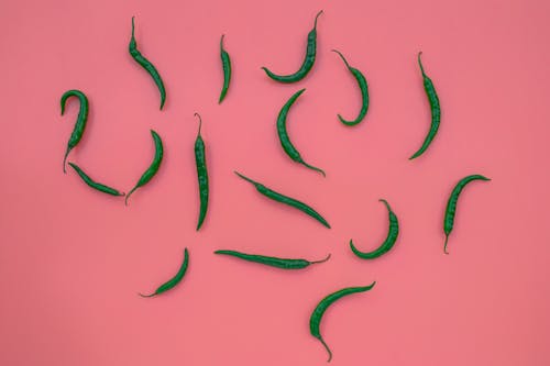 A Green Chili Peppers on a Pink Surface