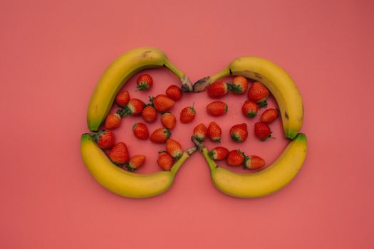 粉红色背景上，成熟的香蕉和草莓充满活力，非常适合美食主题