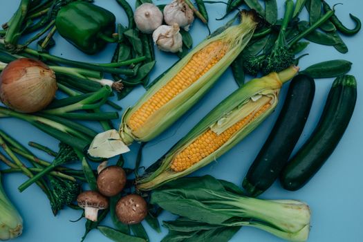 A colorful assortment of fresh organic vegetables spread on a blue background.