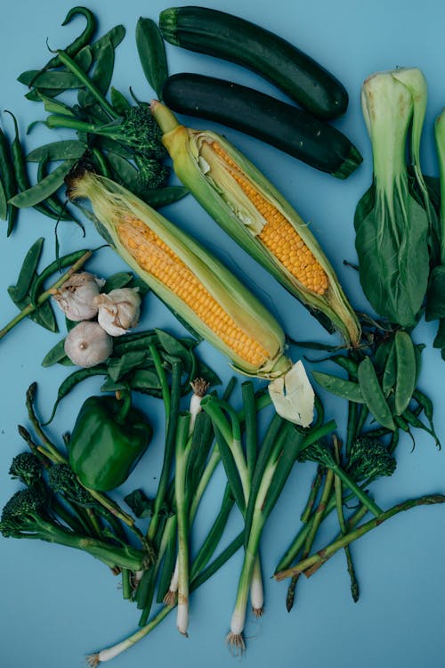 Sweet Corn and Green Vegetables on Blue Surface