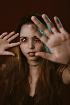 画中一位女子画着令人毛骨悚然的万圣节妆容，她举起双手，营造出一种怪异的氛围