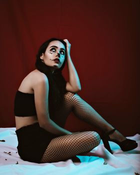 工作室里，一名穿着黑色短裤和渔网紧身裤的女子，以青少年为主题创作艺术肖像