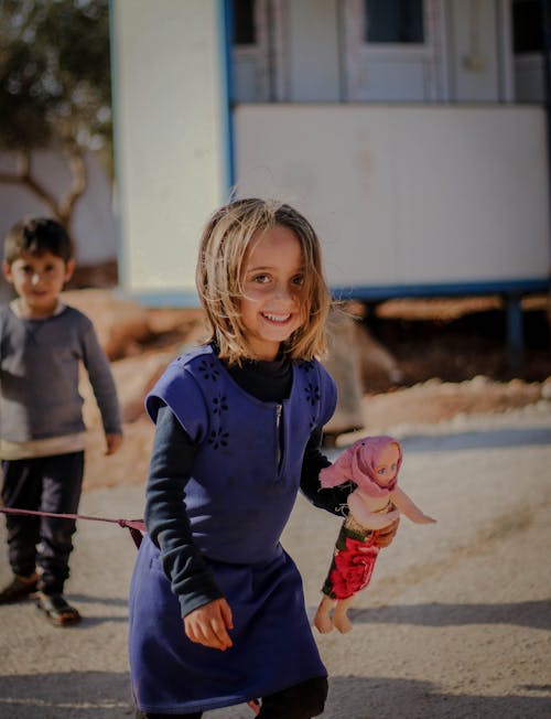 Young Girl in Blue Dress Holding a Doll