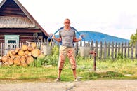 Man Carrying Buckets Standing Near a Fence