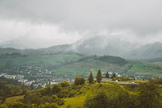 Serene view of a misty mountain landscape with a small village in the foreground.