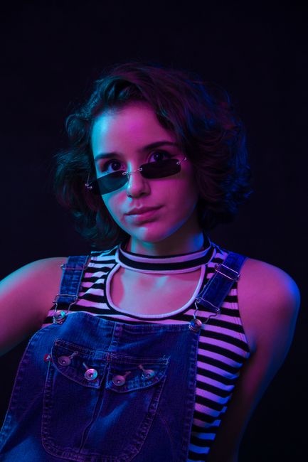 Portrait of a woman in denim and sunglasses with creative lighting, capturing a modern, artistic vibe.