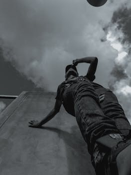 Dramatic low angle shot of a man in gripping monochrome against a cloudy sky.