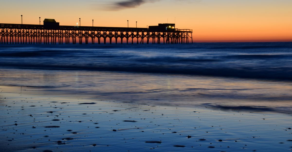 Silhouette of Myrtle Beach pier against a vibrant sunset sky.