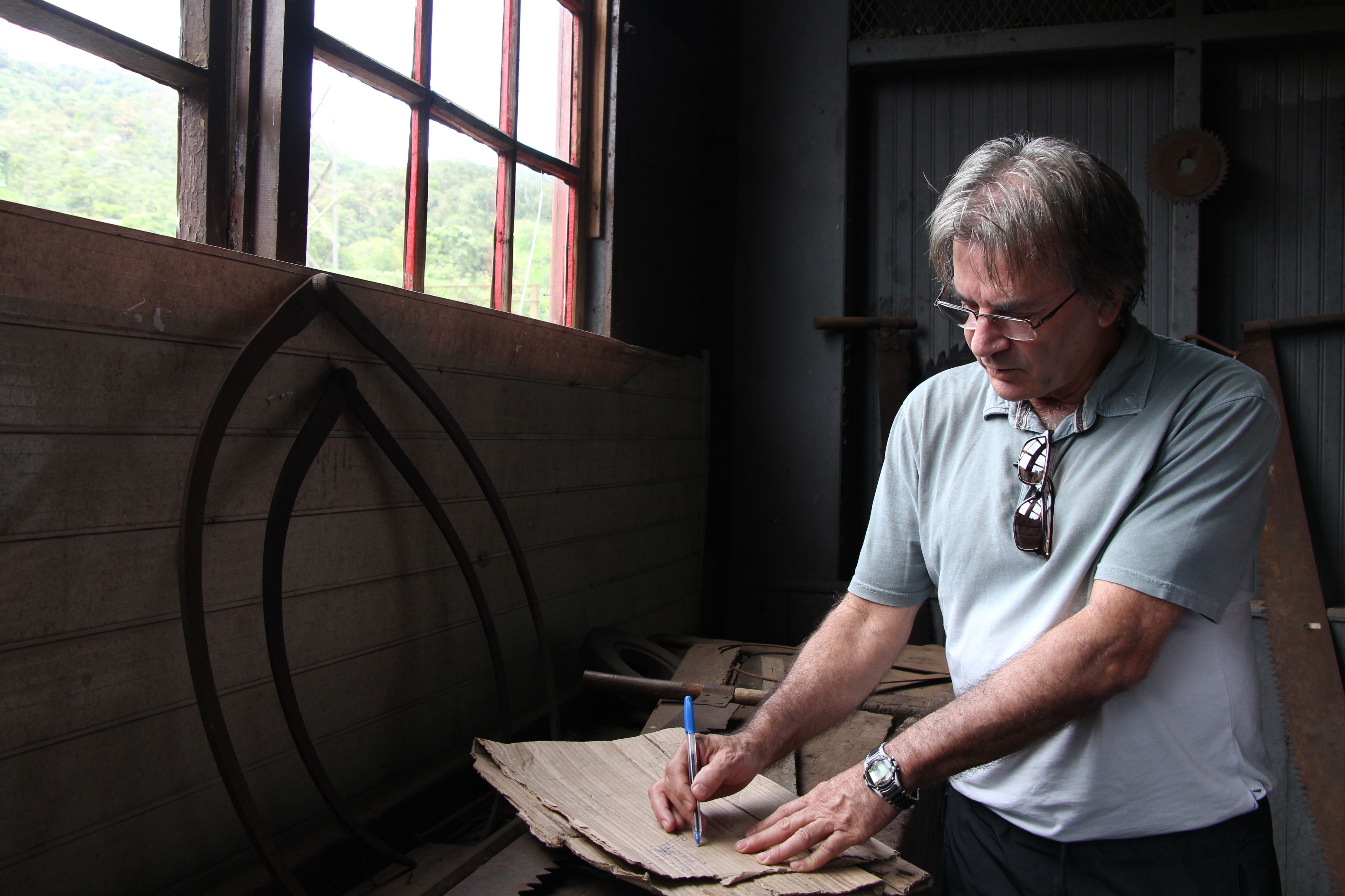 Adult man writing on cardboard in a vintage workshop setting, focusing on craftsmanship and creativity.