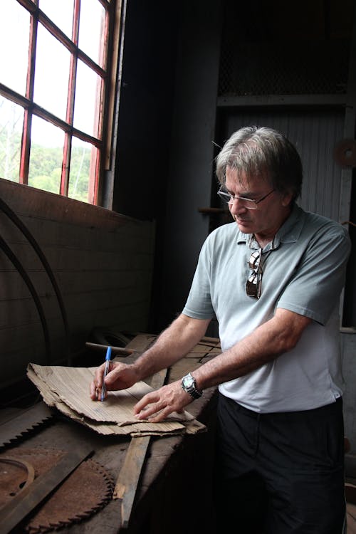 Man in Gray Shirt Writing on a Cardboard