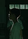 Side View of a Boy in a T-shirt Standing in a Dark Room