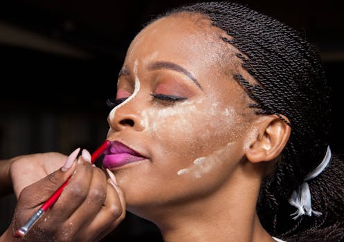 Close-up of a black woman having purple lipstick professionally applied.