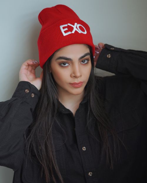 Free Portrait of a woman wearing a red beanie with EXO logo in a casual setting. Stock Photo