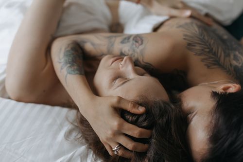 Free Close-up of a loving couple embracing in an intimate moment on a bed, showcasing tattoos and affection. Stock Photo
