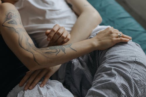 Женщина в белой майке с черной татуировкой на левой руке