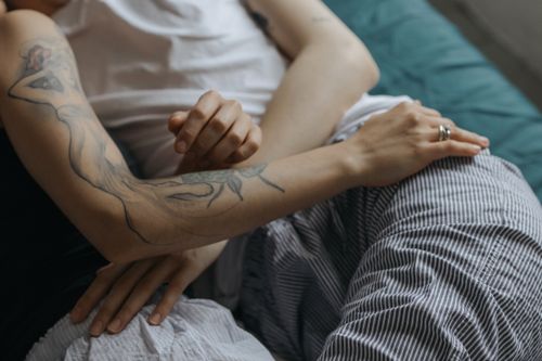 Free Close-up of an intimate embrace between a couple lying together in bed, expressing love and affection. Stock Photo