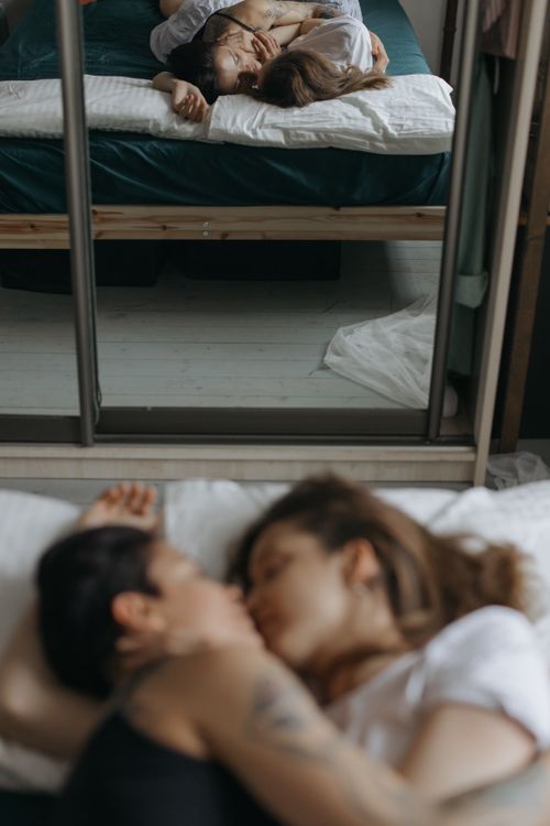 Free A couple embracing intimately on the bed, with a reflection in the mirror conveying love and togetherness. Stock Photo