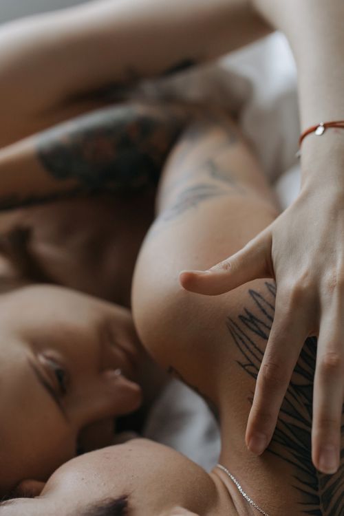 Free A romantic and intimate embrace between a tattooed couple in bed, showcasing love and affection. Stock Photo