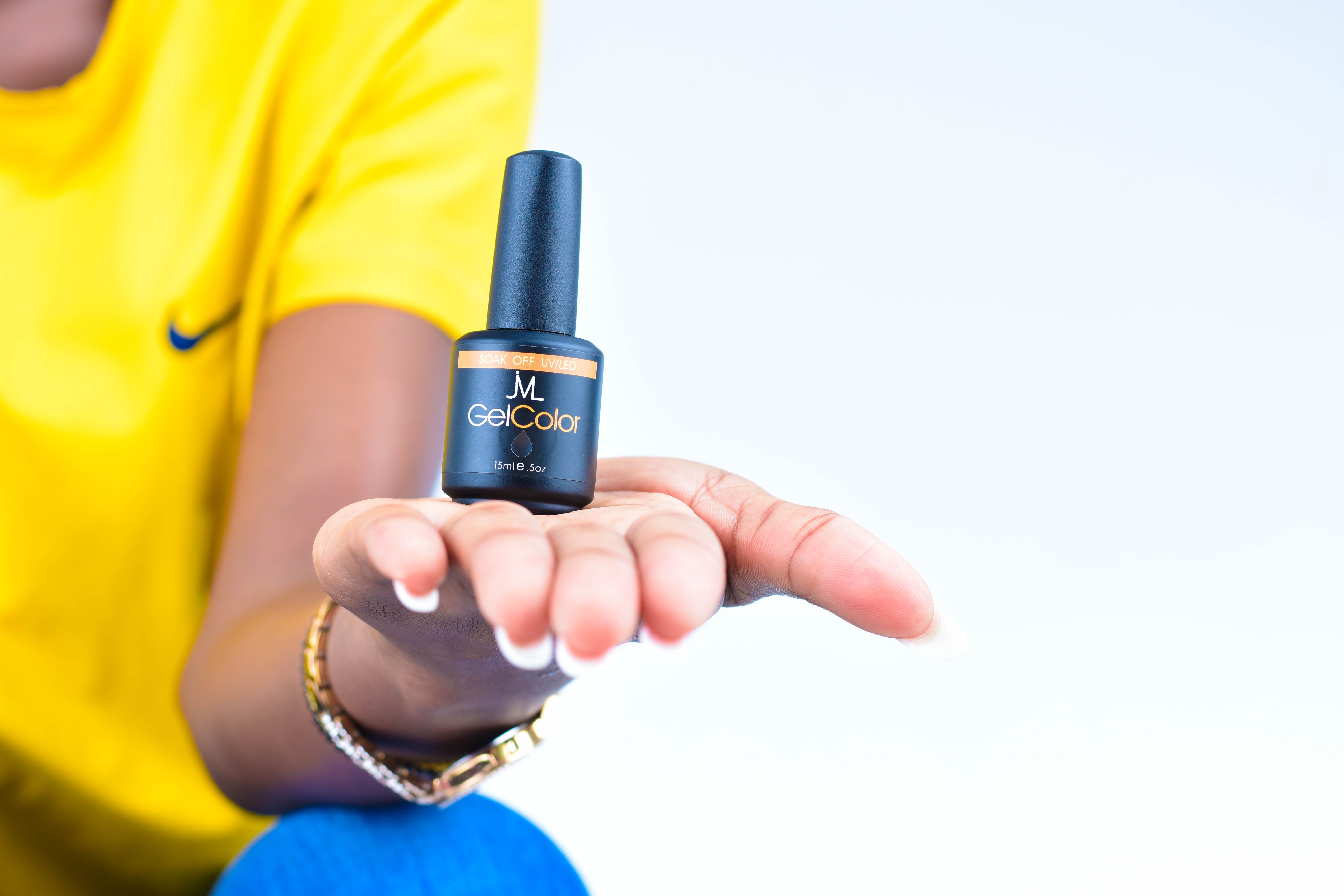 A close-up image of a hand holding a gel nail polish bottle, showcasing beauty and wellness.