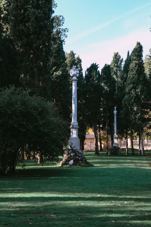 Free Beautiful vertical columns in El Capricho Park, surrounded by lush trees and grass in sunlight. Stock Photo