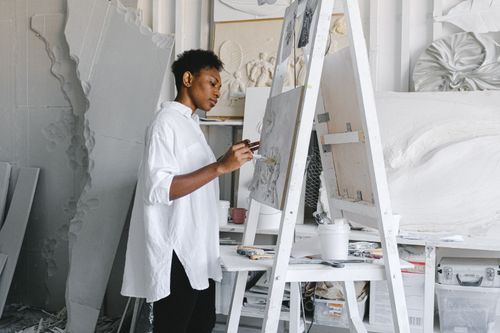 Free Black female artist painting on canvas in a modern studio environment, expressing creativity and artistry. Stock Photo