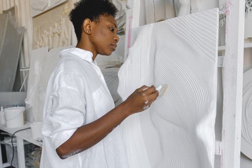 Free A focused artist in a studio works on a textured white artwork with precision. Stock Photo