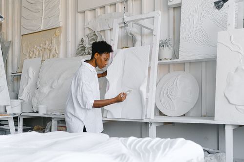Free A talented artist focuses on sculpting a textured artwork in a bright studio space. Stock Photo