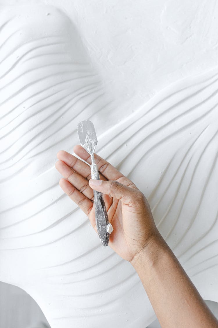 Close-up Of Sculptor Holding Spatula On White Background