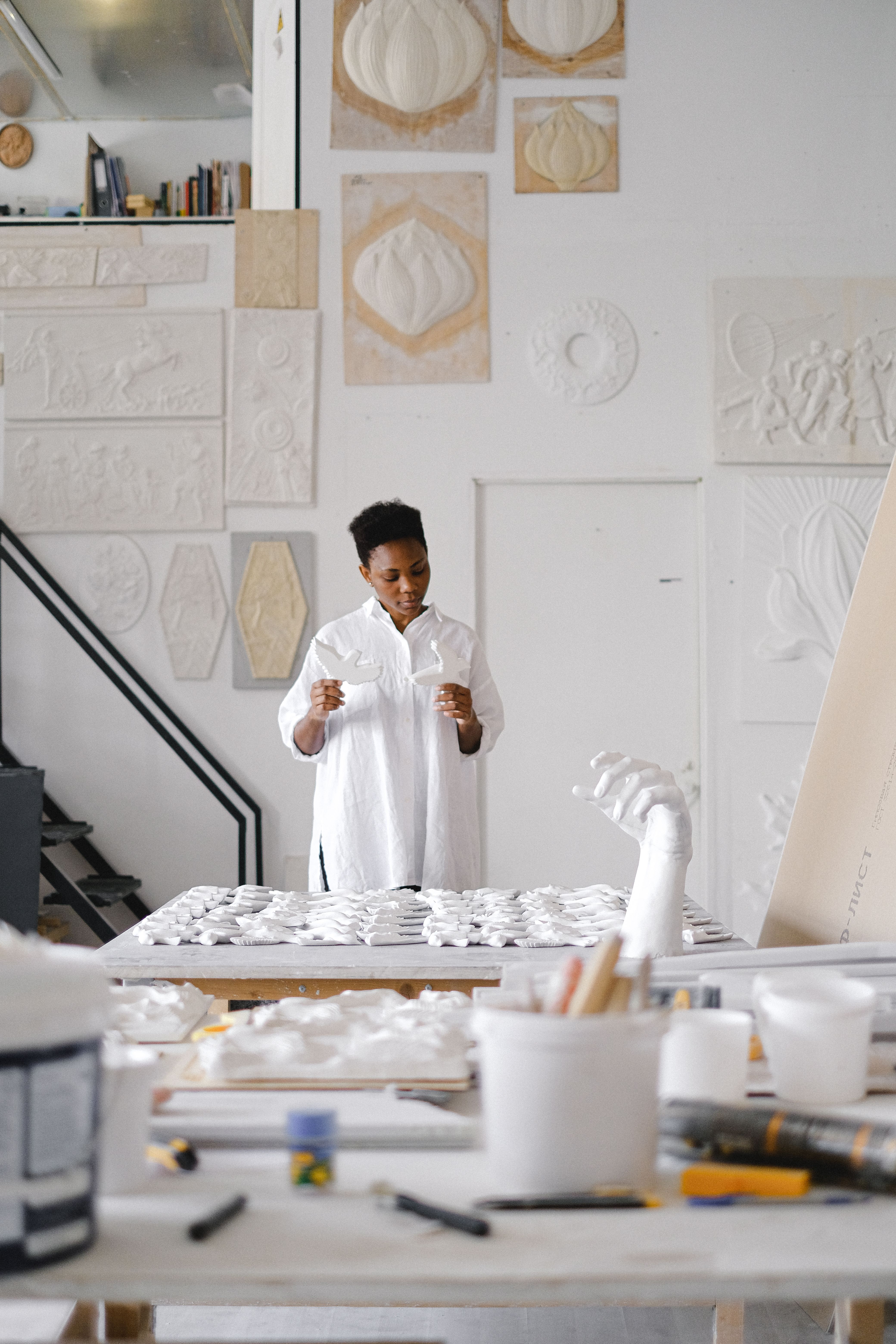 A focused artist creates sculptures in a contemporary studio setting filled with plaster art pieces.