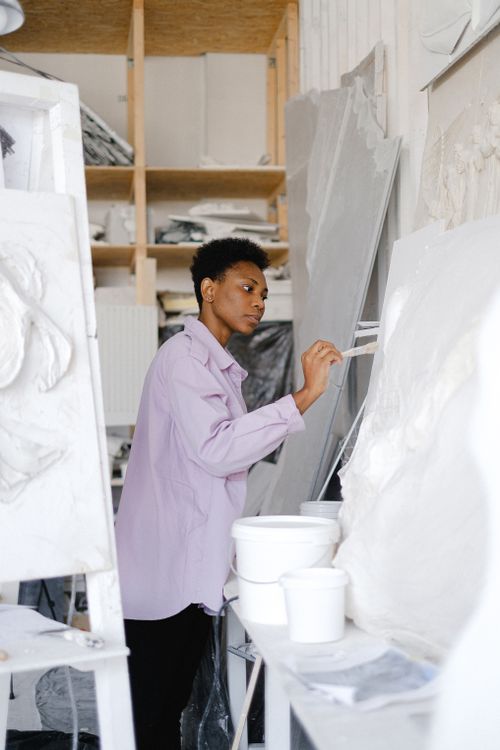 Free Black woman artist in studio working on sculptures, focused expression. Stock Photo