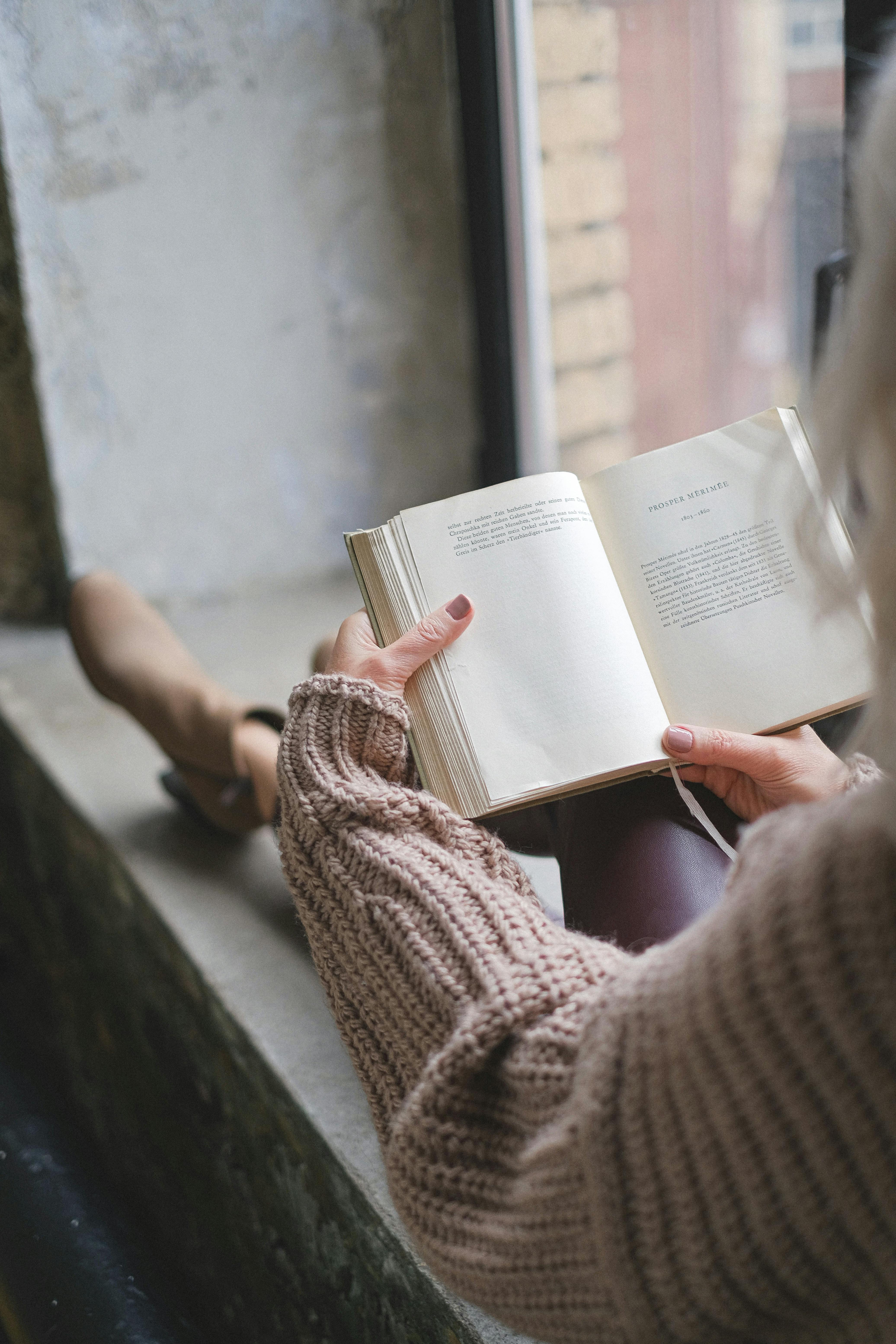 a person in a sweater reading a book