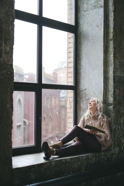 Woman in White Sweater Sitting on Window