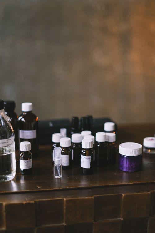 Free A variety of small bottles with white caps arranged on a wooden table in a dimly lit interior setting. Stock Photo